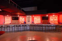 Banquet hall entertainment center with full bar with red ambient lighting by Paramount Construction and Contracting
